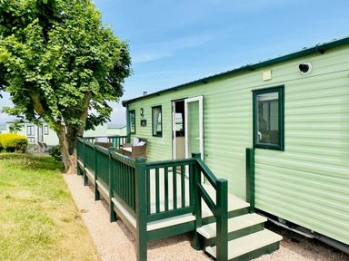 a mobile home with a green exterior and steps leading to a deck at St Andrews Holiday Park - Holiday Accommodation 609, St. Andrews
