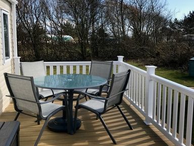 a dining table with chairs on a deck at Greenacres Holiday Park - Holiday Accommodation 6757 in Porthmadog
