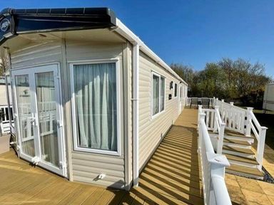 a mobile home with a deck and railing at Greenacres Holiday Park - Holiday Accommodation 6757 in Porthmadog