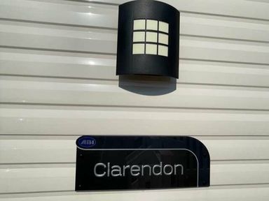 a wall with a light fixture and a sign labeled Clarendon at Greenacres Holiday Park - Holiday Accommodation 6757, Porthmadog