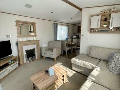 a living room with a TV, sofa, and dining area at Greenacres Holiday Park - Holiday Accommodation 6757 in Porthmadog