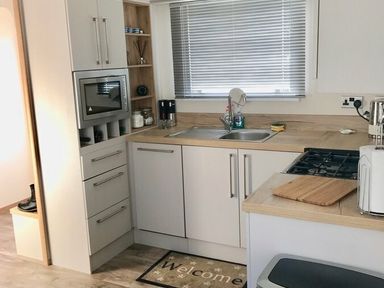 a modern kitchen with a sink, microwave, and stove at Greenacres Holiday Park - Holiday Accommodation 6757, Porthmadog
