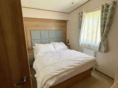 a bedroom with a double bed and window dressed with curtains at Greenacres Holiday Park - Holiday Accommodation 6757 Porthmadog