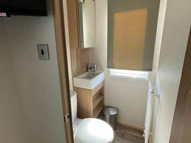 a bathroom with a sink, toilet, and window at Greenacres Holiday Park - Holiday Accommodation 6757, Porthmadog