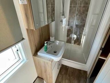 a bathroom with a sink, shower, and mirror at Greenacres Holiday Park - Holiday Accommodation 6757, Porthmadog
