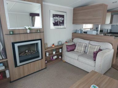 a living room with a fireplace and sofa at Reighton Sands Holiday Park - Holiday Accommodation 6837, Filey