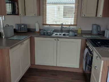 a kitchen with cabinets, sink, and appliances at Reighton Sands Holiday Park - Holiday Accommodation 6837 in Filey