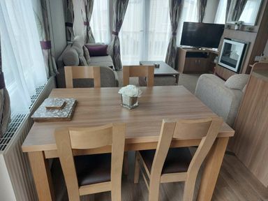 a dining area with a wooden table and chairs in a living room at Reighton Sands Holiday Park - Holiday Accommodation 6837 in Filey
