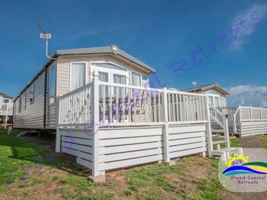 a holiday caravan with a deck and patio furniture at Grand Coastal Retreats in an outdoor setting
