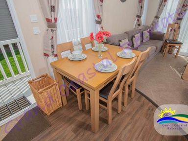 a dining table set with plates and flowers next to a sofa at Grand Coastal Retreats