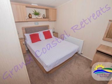 a bedroom with a double bed and red cushions at Devon Cliffs Holiday Park - Holiday Accommodation 6955, Exmouth