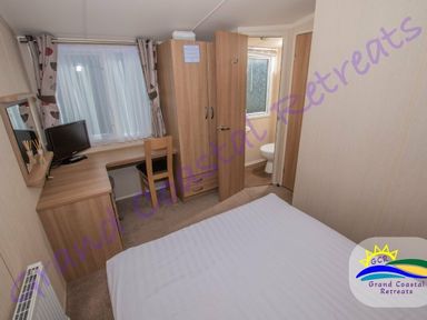 a bedroom with a bed, desk, and chair at Grand Coastal Retreats