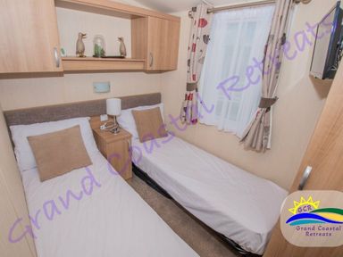 a bedroom with two single beds and a bedside table at Grand Coastal Retreats