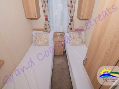 a bedroom with two single beds and a bedside table at Grand Coastal Retreats