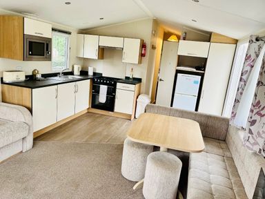 a kitchen and living area with a dining table and seating at Hafan y Mor Haven - Holiday Accommodation 7421 in Pwllheli