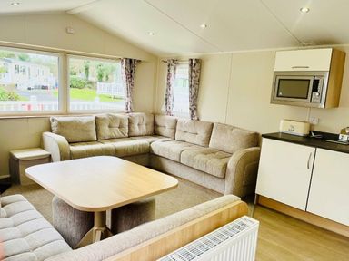 a living room with a sectional sofa and a table at Hafan y Mor Haven - Holiday Accommodation 7421 Pwllheli