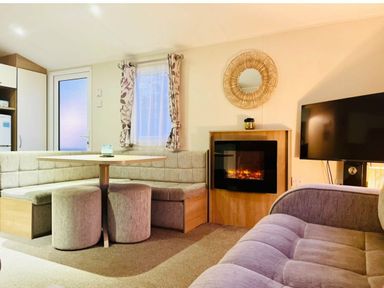 a seating area with a round table and a fireplace at Hafan y Mor Haven - Holiday Accommodation 7421 Pwllheli