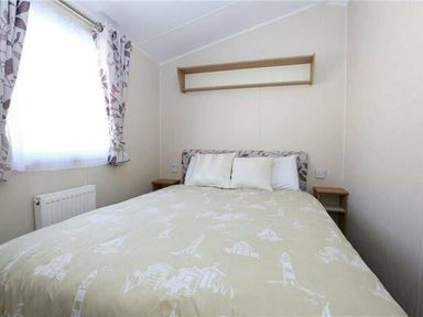 a bedroom with a double bed and shelves at Hafan y Mor Haven - Holiday Accommodation 7421 in Pwllheli