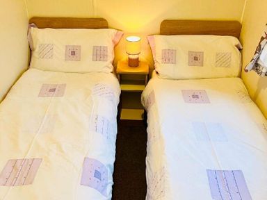 a bedroom with two single beds and a lamp on a nightstand at Hafan y Mor Haven - Holiday Accommodation 7421 Pwllheli