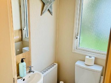 a small bathroom with a sink, toilet, and window at Hafan y Mor Haven - Holiday Accommodation 7421 Pwllheli