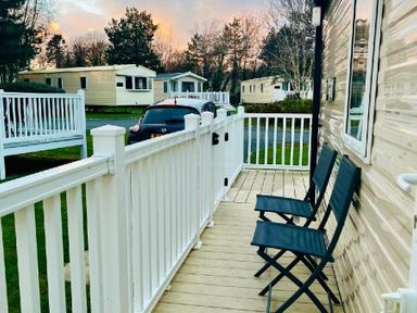 a porch area with two chairs and a view of mobile homes at Hafan y Mor Haven - Holiday Accommodation 7421 Pwllheli