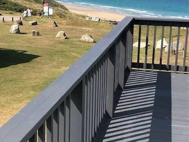a view from a balcony overlooking a beach with grass and rocks at Perran Sands - Holiday Accommodation 7528, Perranporth, Cornwall, United Kingdom
