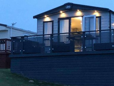 a lodge with a balcony and outdoor seating area at Perran Sands - Holiday Accommodation 7528, Perranporth, Cornwall, United Kingdom