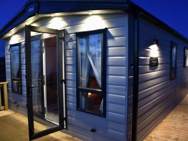 an exterior view of a holiday cabin with lights at Perran Sands - Holiday Accommodation 7528, Perranporth, Cornwall, United Kingdom