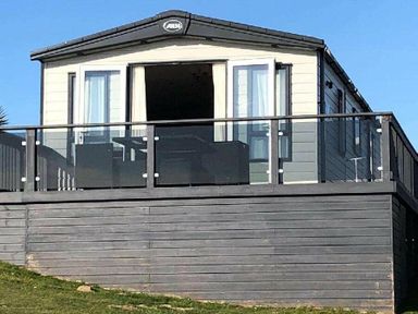 a holiday home with a balcony and large windows at Perran Sands - Holiday Accommodation 7528 Perranporth, Cornwall, United Kingdom