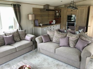 a living room with two sofas and a kitchen area at Perran Sands - Holiday Accommodation 7528, Perranporth, Cornwall, United Kingdom