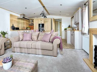 a living room with a sofa, kitchen area, and kitchen appliances at Perran Sands - Holiday Accommodation 7528 Perranporth, Cornwall, United Kingdom