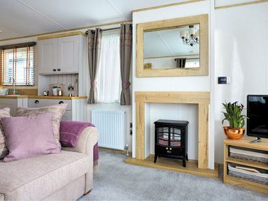 a living room with a fireplace and mirror at Perran Sands - Holiday Accommodation 7528 in Perranporth, Cornwall, United Kingdom