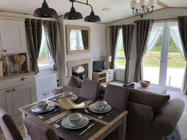 a dining area with a table set for four and a seating area at Perran Sands - Holiday Accommodation 7528, Perranporth, Cornwall, United Kingdom