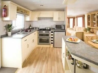 a kitchen with cabinets, appliances, and a dining area at Perran Sands - Holiday Accommodation 8131 in Perranporth