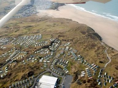 an aerial view of a coastline with a beach and a caravan site with marked areas at Perran Sands - Holiday Accommodation 8131 Perranporth