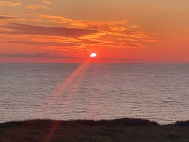a sunset over the ocean with orange and red hues at Perran Sands - Holiday Accommodation 8131 in Perranporth