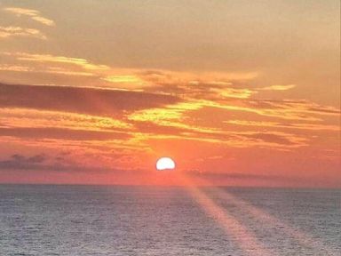 a sunset over the ocean with orange and yellow hues at Perran Sands - Holiday Accommodation 8131 Perranporth