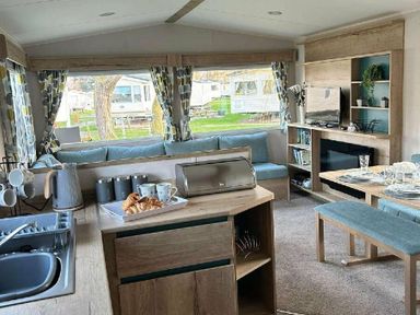 a living room and kitchen area with a sofa, dining table, and kitchen appliances at Butlins Minehead - Holiday Accommodation 826 in Minehead