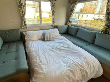 a bed with white bedding in a corner seating area at Butlins Minehead - Holiday Accommodation 826, Minehead