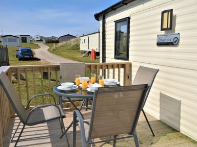 a dining table with drinks on a wooden deck at Perran Sands - Holiday Accommodation 8302 in Perranporth