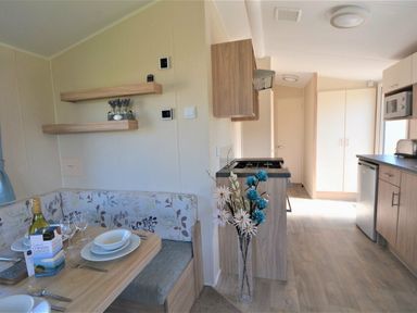 a dining area with a table set for four and a kitchen in Perran Sands - Holiday Accommodation 8302, Perranporth