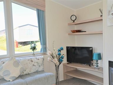 a living room with a TV on a shelf and a window at Perran Sands - Holiday Accommodation 8302 in Perranporth