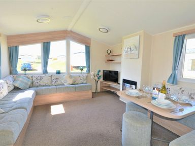 a living room with a sofa, dining table, and television at Perran Sands - Holiday Accommodation 8302, Perranporth