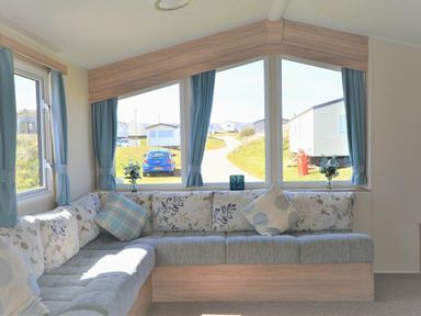 a living room with a gray sectional sofa and large windows at Perran Sands - Holiday Accommodation 8302, Perranporth