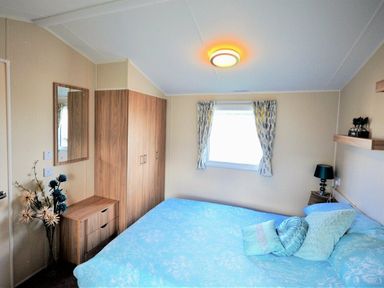 a bedroom with a bed, bedside table, mirror, and wardrobe at Perran Sands - Holiday Accommodation 8302, Perranporth