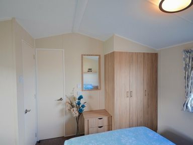 a bedroom with a double bed, wardrobe, mirror and a door at Perran Sands - Holiday Accommodation 8302, Perranporth