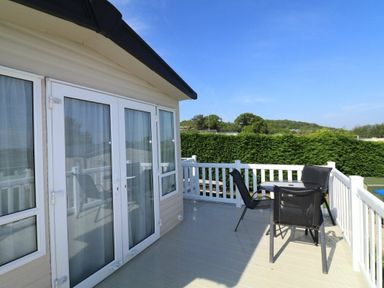 a balcony with chairs and a table overlooking greenery at White Acres Holiday Park - Holiday Accommodation 895 in Newquay