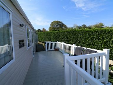 a deck area with a railing and chairs at White Acres Holiday Park - Holiday Accommodation 895 in Newquay