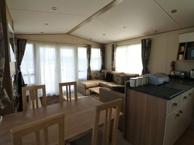 a living room with a sofa and dining area at White Acres Holiday Park - Holiday Accommodation 895, Newquay