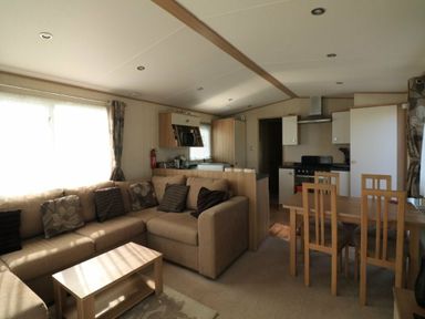 a living room with a sofa and dining table at White Acres Holiday Park - Holiday Accommodation 895 in Newquay
